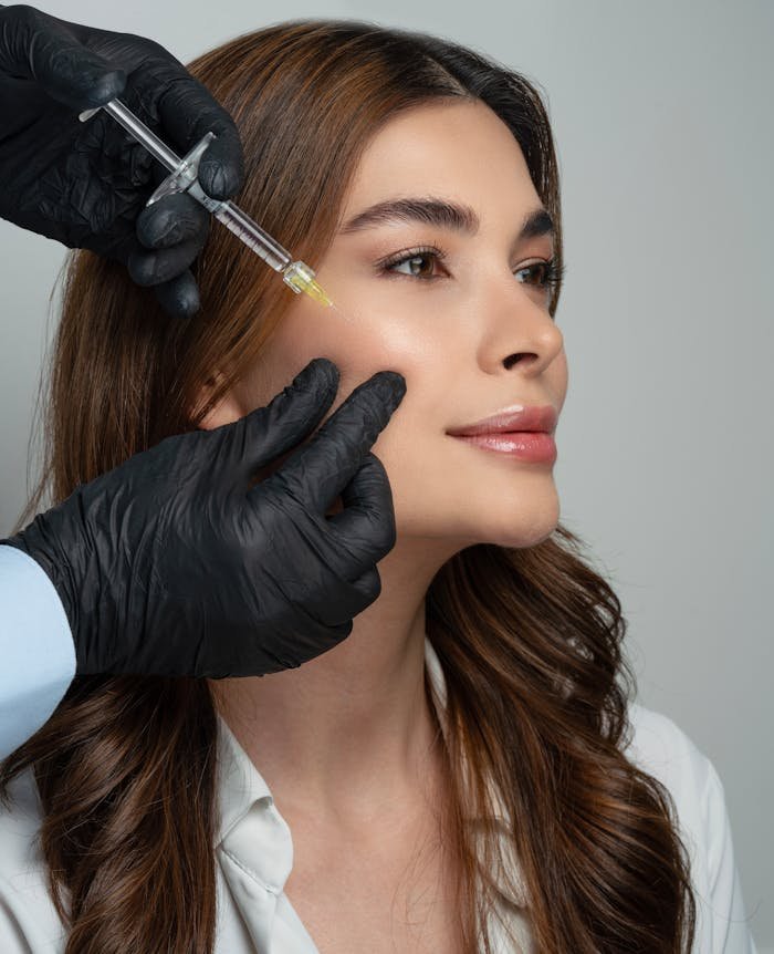 A beautician administering a cosmetic injection to a woman in a clinical setting.