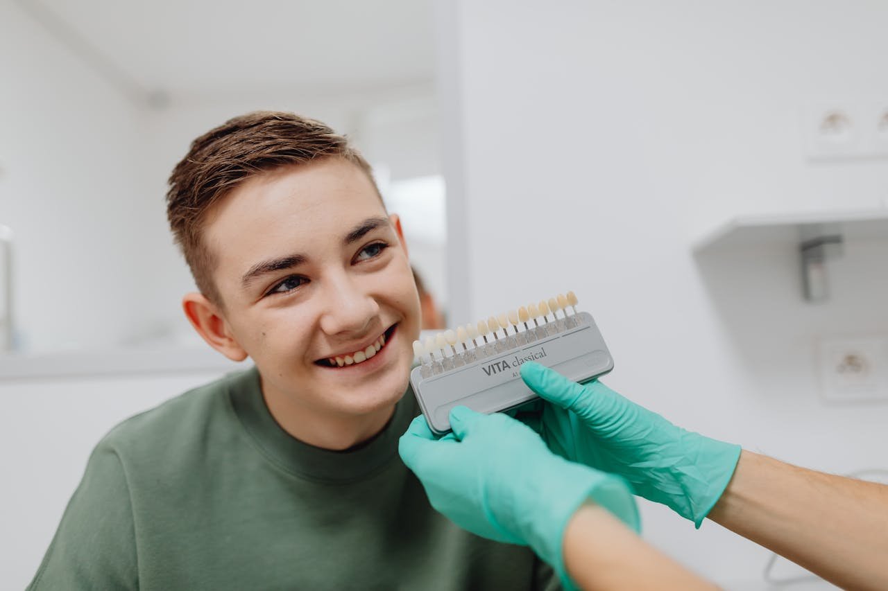 A teenager smiling during a dental shade matching procedure at a dentist office.